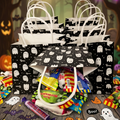 A set of black Halloween candy bags with white ghost patterns and white paper handles, filled with assorted candy, arranged on a wooden surface with Halloween decorations including stickers, pumpkins, and string lights in the background.