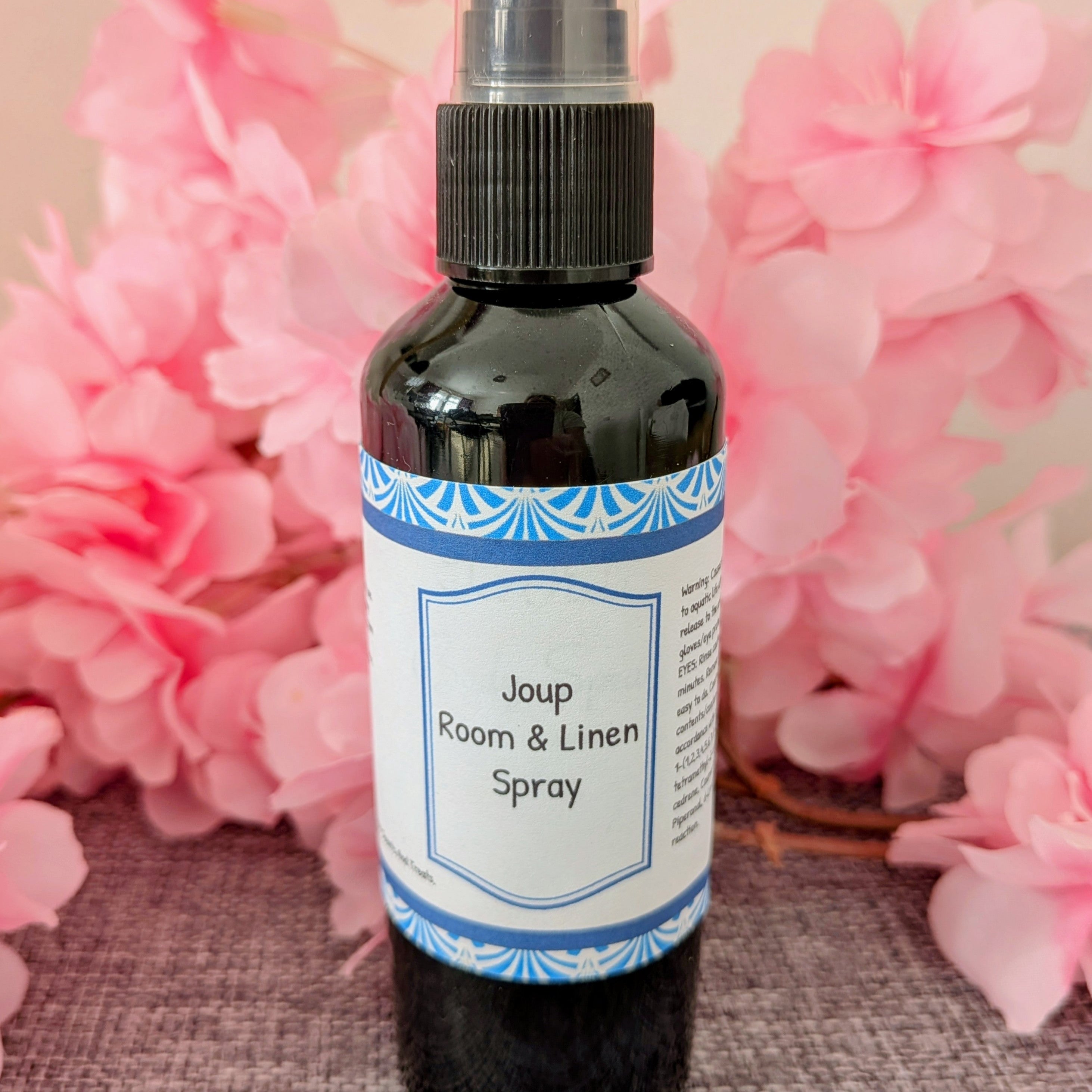 Joup Room & Linen Spray bottle with pink flowers in the background