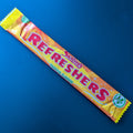 A single wrapped Swizzles Refreshers Tropical Flavour candy bar on a solid dark blue background.